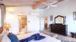 A spacious bedroom with a large bed, a ceiling fan, a dresser, and a mirror. - Modern 2-bed Apt Near Beach In St. Lawrence Gap 2 Bedroom Apts by Bluescape (St. Lawrence Gap)