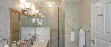 A bathroom with two sinks, a glass shower enclosure, and a white door.