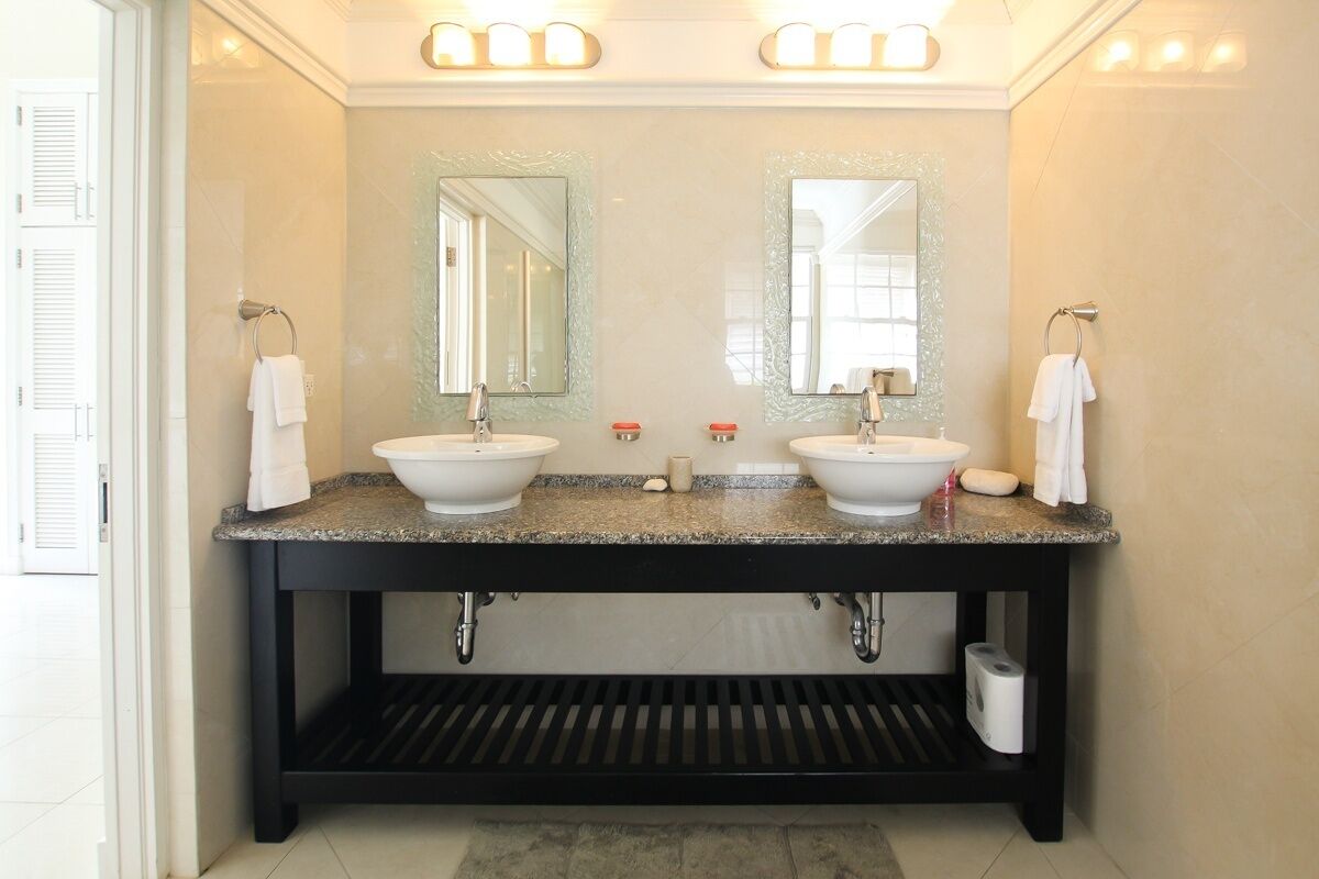 A bathroom with two sinks, a mirror, and a towel rack.