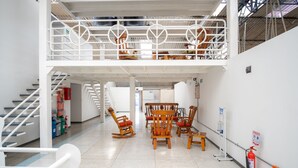 Un vestíbulo amplio con techo alto, una escalera y varias sillas mecedoras de madera.