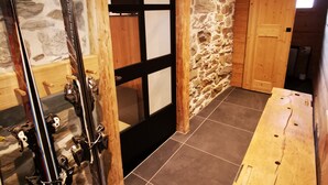 A wooden interior with a stone wall, a wooden door, and a table. - New chalet Méribel (Méribel)