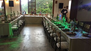 Une longue table à manger, entourée de chaises, mise avec des assiettes, des verres et des fleurs.