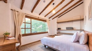 Une chambre à coucher avec un lit, un bureau avec une chaise, une fenêtre avec des rideaux et une étagère avec un livre.