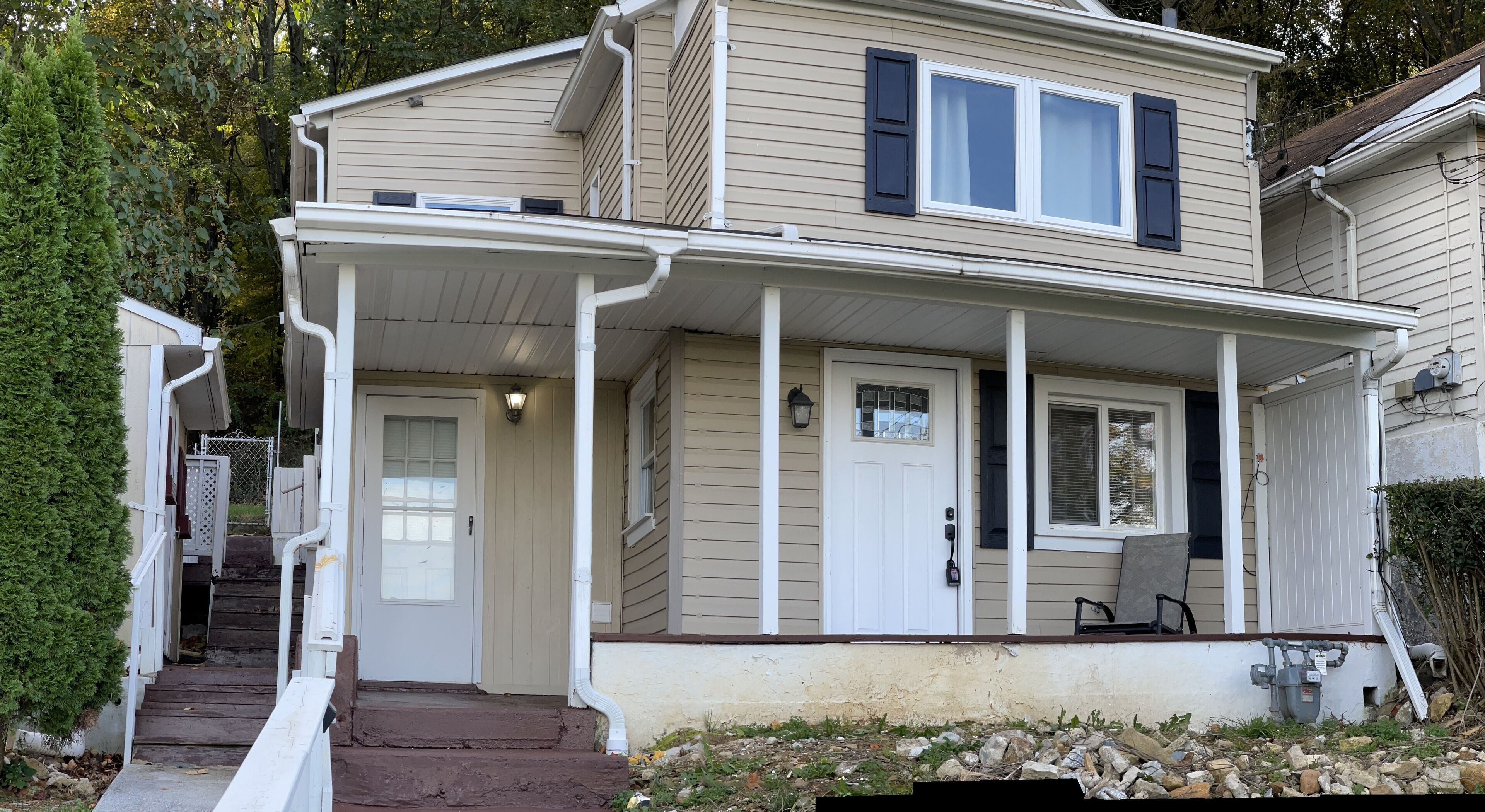 A two-story house with a front porch, a door, and a small window.