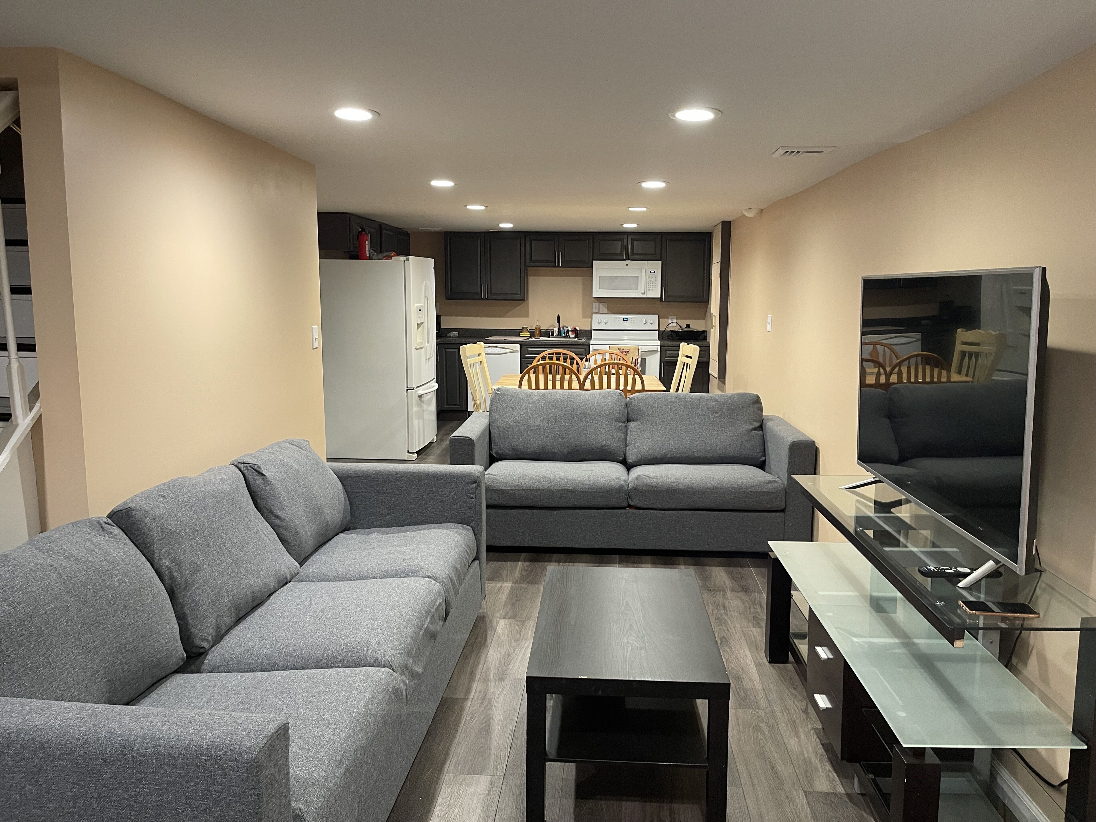 A modern living room with grey sofas, a glass coffee table, and a flat-screen TV.