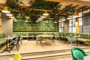 Un restaurante con paredes verdes, vigas de madera y lámparas colgantes.