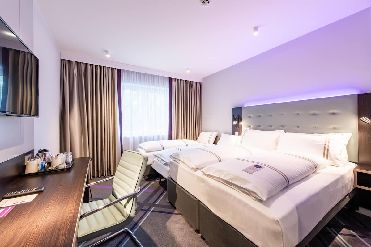 A hotel room with a bed, a desk, a chair, a TV, and curtains.