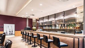 Uma área de bar com vários bancos, balcão e diversas garrafas.