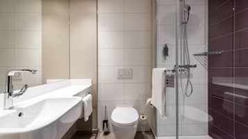 A modern bathroom with a large white sink, a toilet, and a glass-enclosed shower area.