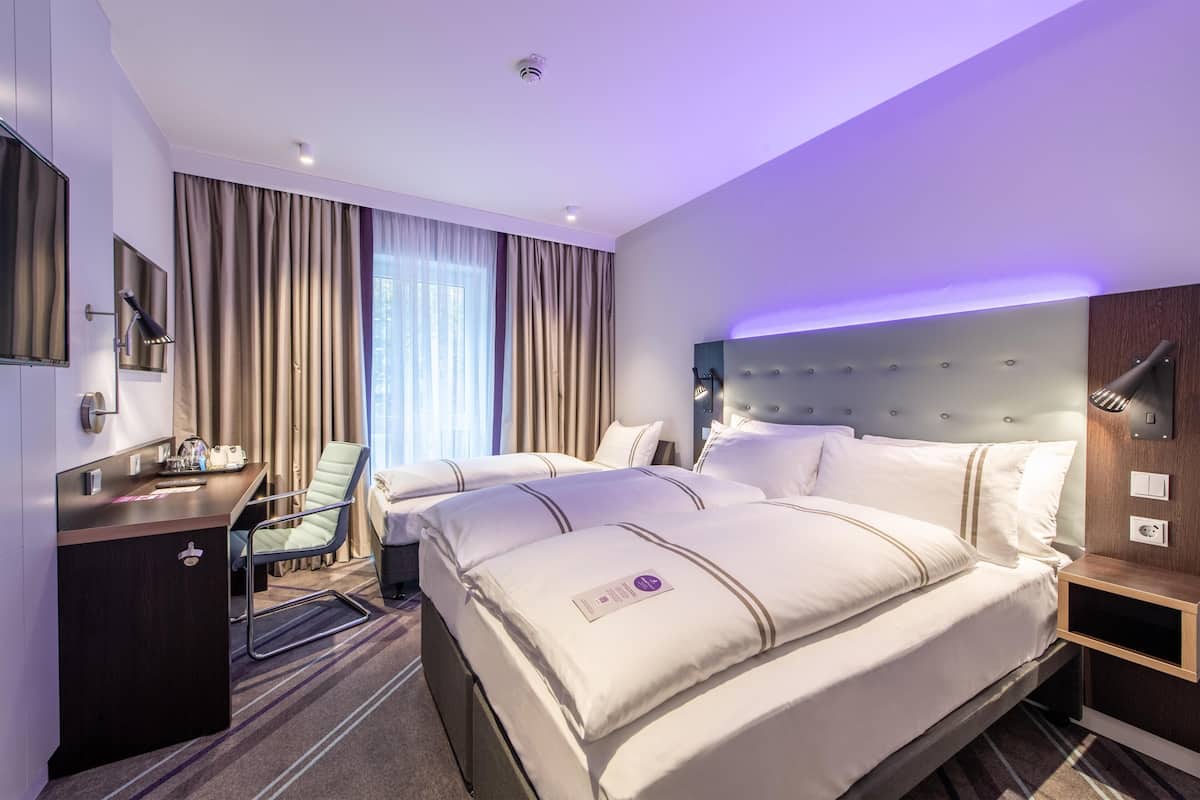 A hotel room with a large bed, a desk, a chair, and a television.