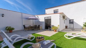A patio with a table and chairs, a lounge chair, and a small garden area. - Casa Verde de Elena Benalauría by Ruralidays (Málaga)