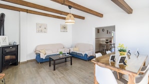 A modern living room with a sofa, a coffee table, and a dining area with chairs and a glass table. - Casa Verde de Elena Benalauría by Ruralidays (Málaga)