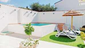 A swimming pool with a small tree, a couple of lounge chairs, and a decorative umbrella. - Casa Verde de Elena Benalauría by Ruralidays (Málaga)