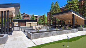 Un'area esterna moderna con un campo da golf, posti a sedere e un edificio con veranda coperta.