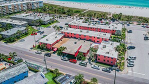 Ett stort hotellkomplex med flera byggnader, en parkeringsplats och en strand i bakgrunden.
