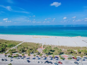 A beach with a parking lot and a view of the ocean.