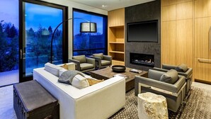 A modern living room with a large window, a fireplace, and a flat-screen TV mounted on the wall. - $7 Million Aspen 4BR Residence - Brand New Construction (Aspen)