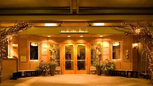 A hotel entrance with a warm, inviting glow, featuring a glass door entrance, potted plants, and a bench area. - $7 Million Aspen 4BR Residence - Brand New Construction (Aspen)