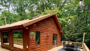 Eine Holzhütte mit einer Terrasse, Sitzgelegenheiten im Freien und einer Feuerstelle.