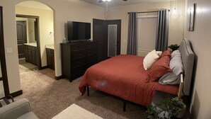A bedroom with a bed, dresser, television, and a ceiling fan.