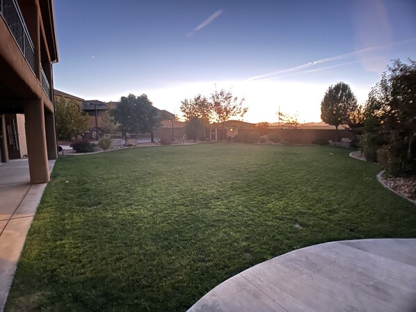 A well-maintained lawn with a clear sky and distant trees.