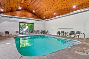 An indoor swimming pool with wooden ceiling beams, a view of greenery outside, and several chairs around the pool area. - Pet Friendly! Views, Pool, 7mi to Dollywood, Golf (Sevierville)