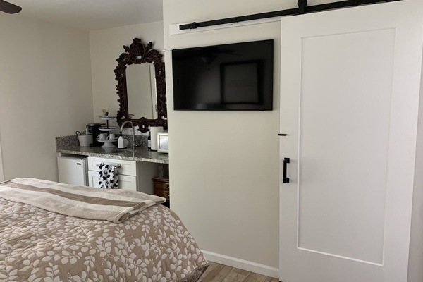 Queen bedroom suite, smart TV, kitchenette, bathroom behind barn door.