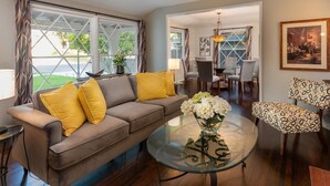A living room with a brown sofa, yellow cushions, a glass coffee table with white flowers, and a patterned armchair. -  PICTURE PERFECT minutes to UNIVERSAL STUDIOS & HOLLYWOOD: Rated 10/10!!! (Los Angeles)