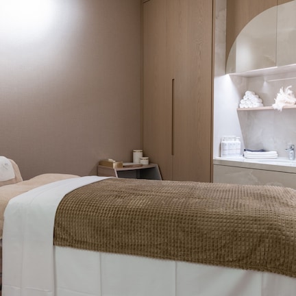 A room with a bed, a mirror, a shelf with toiletries, and a wall with the word "CALM".