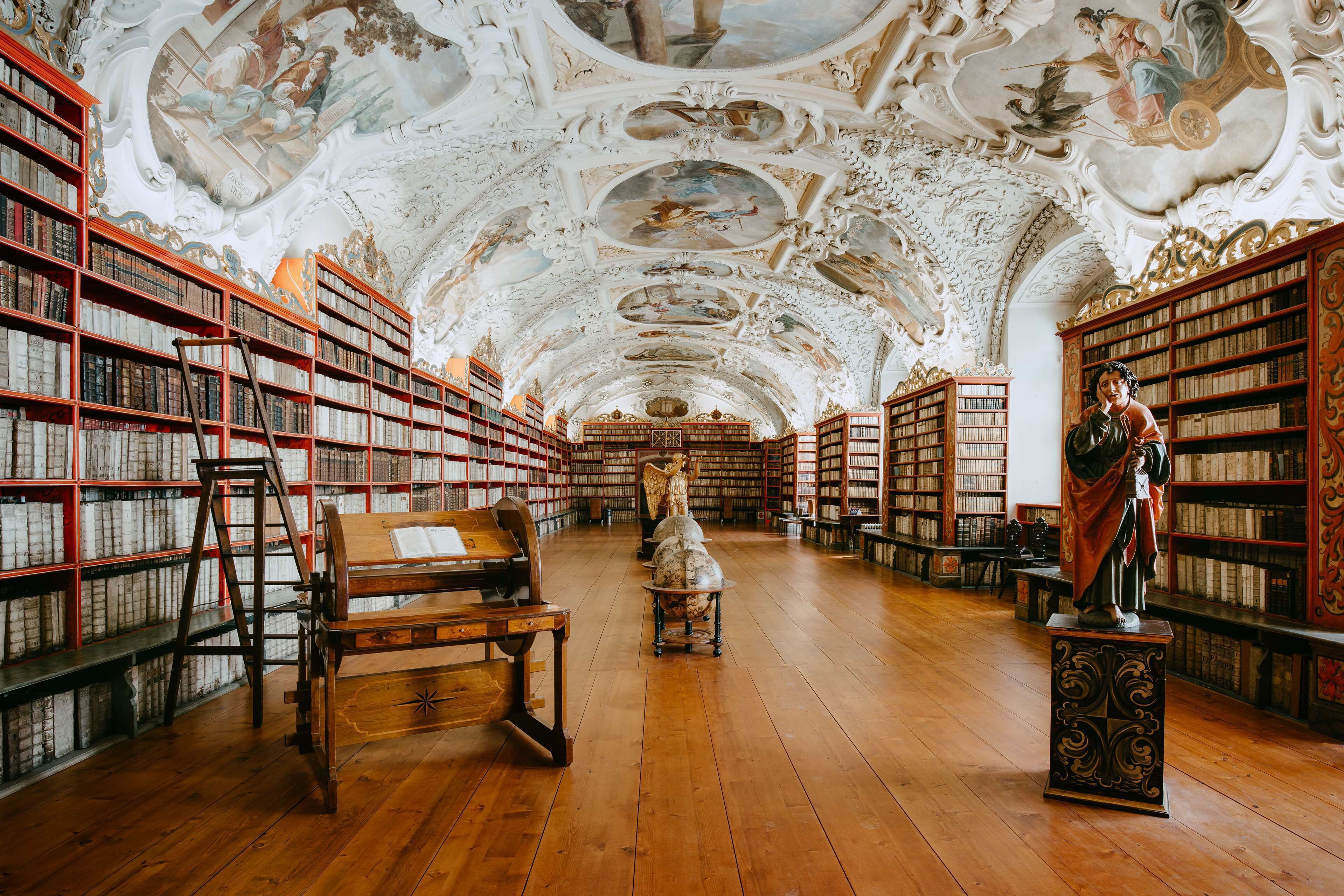 Eine Bibliothek mit aufwendigen Decken, Holzdielen und Bücherregalen voller Bücher.