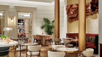 A spacious lobby with multiple seating areas, a central bar, and a large plant.