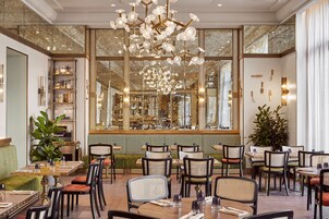 A restaurant interior with a central chandelier, mirrored walls, and a variety of seating arrangements.
