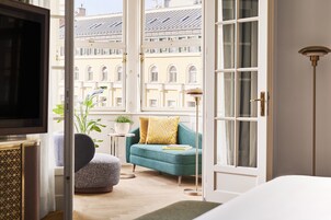A room with a teal sofa, a small table with a plant, and a television on a cabinet.