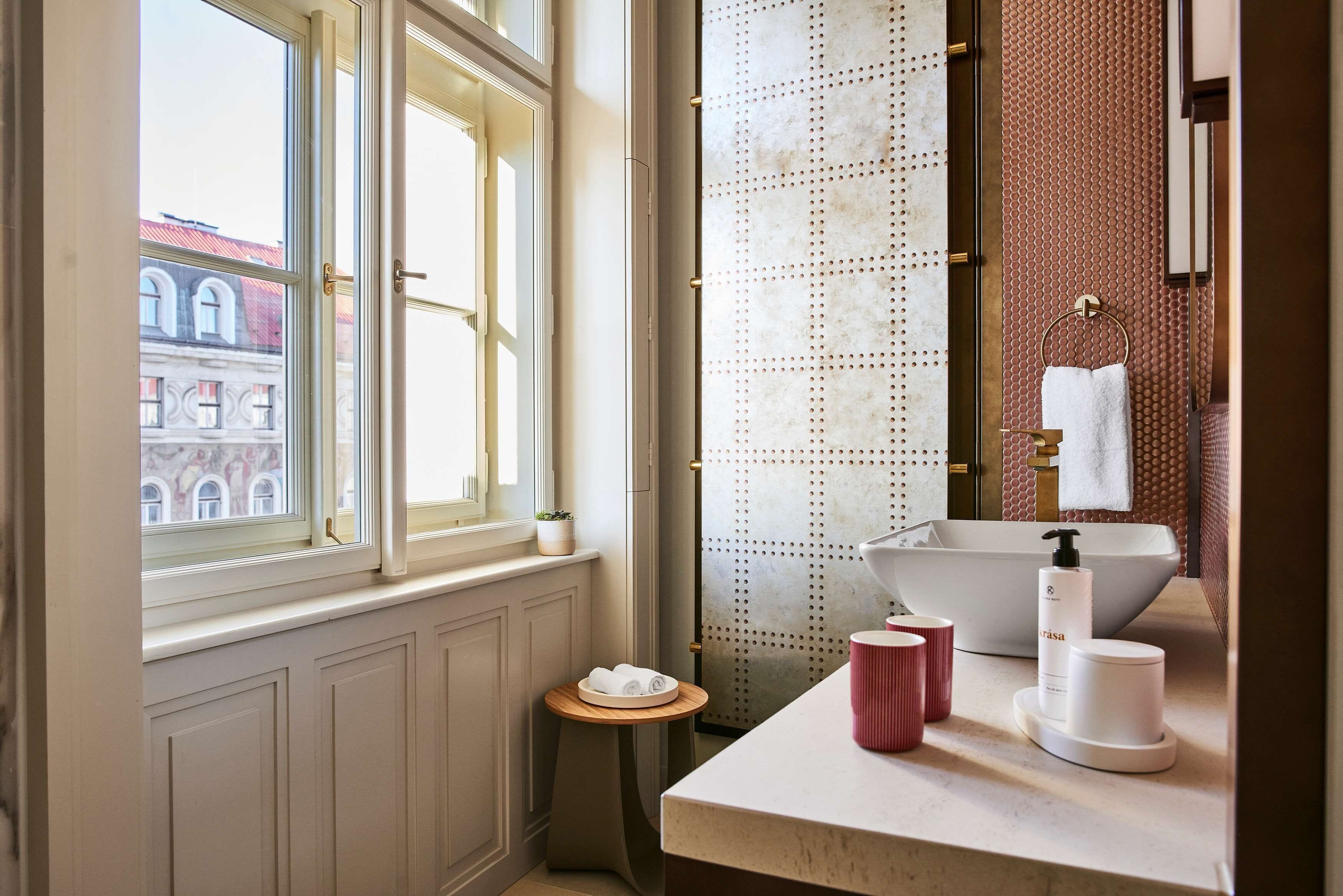 A bathroom with a large window, a sink with a vessel basin, and a small stool.