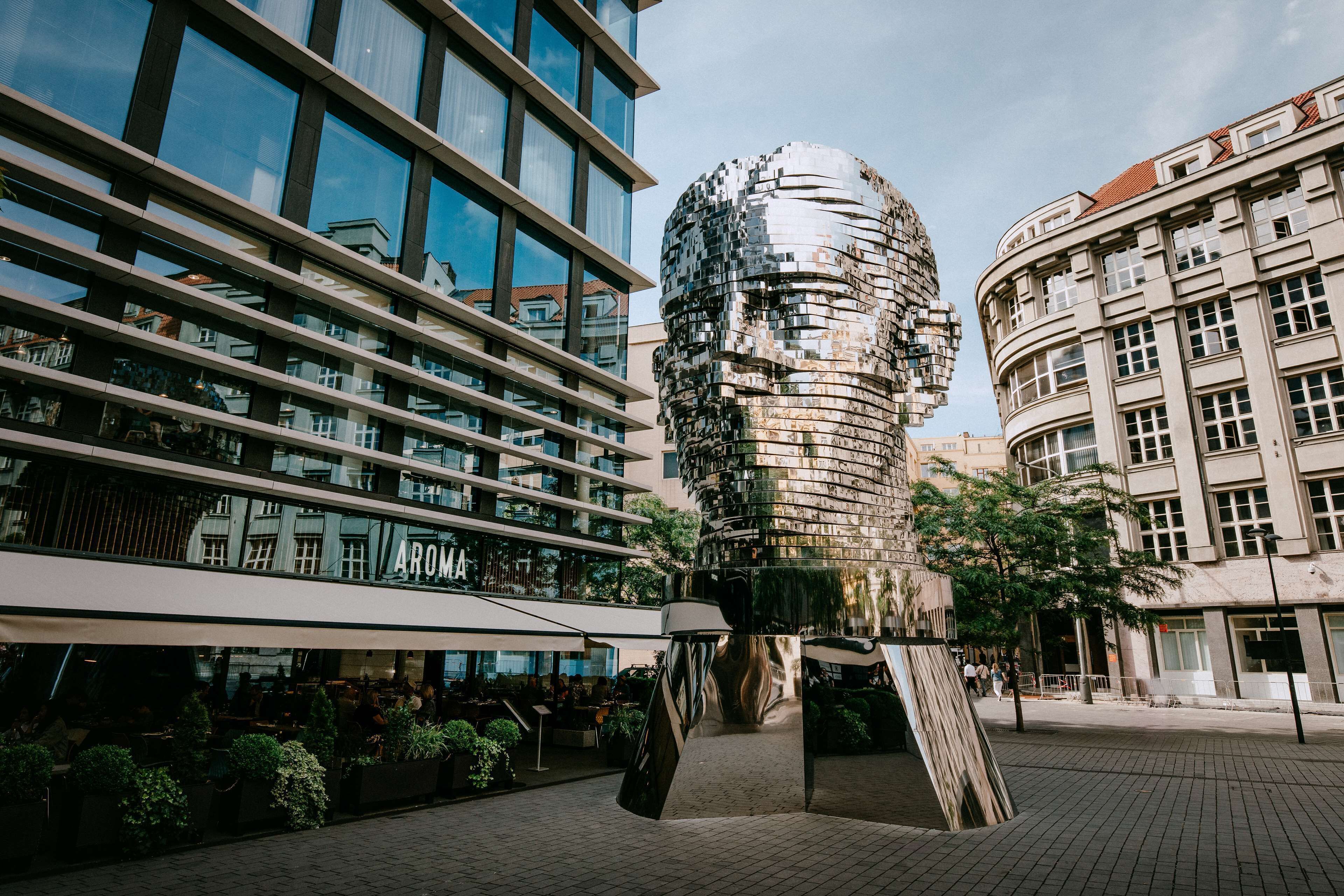 Un edificio moderno con una estructura cilíndrica distintiva y un restaurante llamado "Aroma" con terraza.