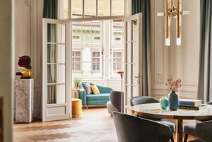 A room with a large open door leading to a balcony, a sofa, a coffee table, and a vase with flowers.