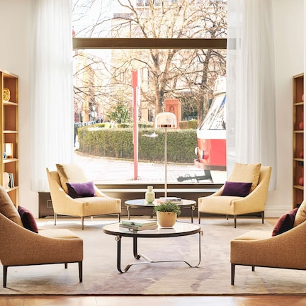 A modern living room with two armchairs, a coffee table, and bookshelves filled with decorative items.