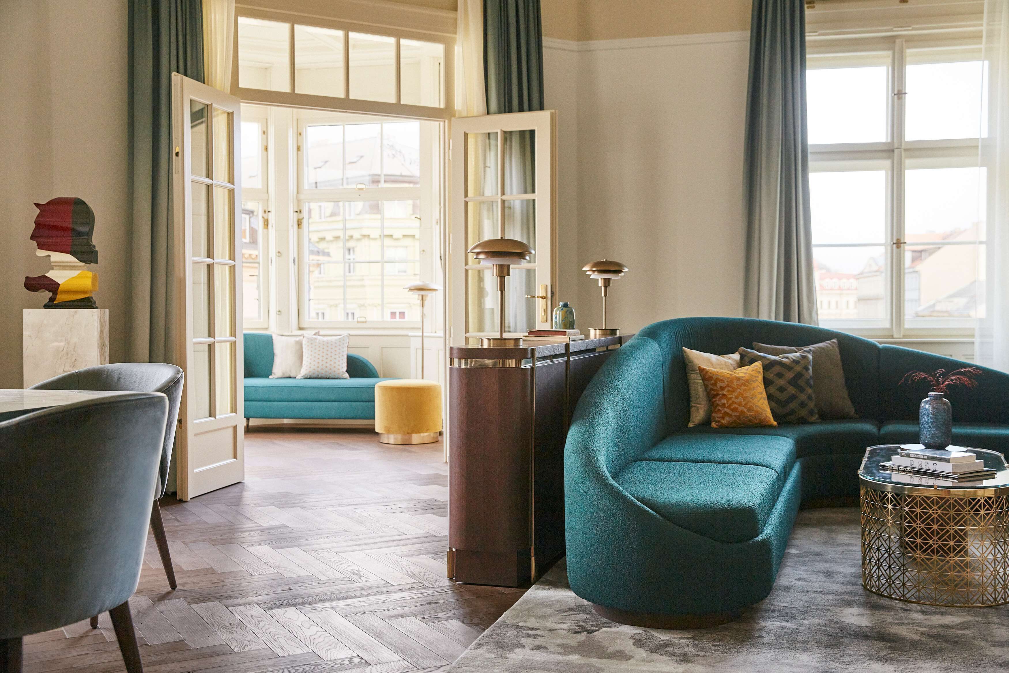 A living room with a teal sofa, a round coffee table, and a tall side table.