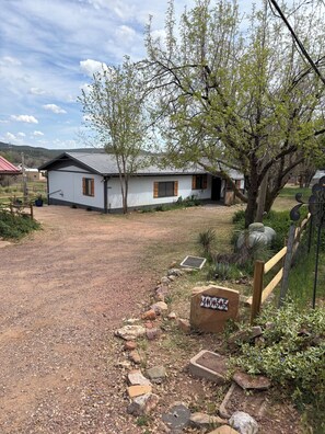 A single-story building with a gravel driveway, a wooden fence, and a sign with the number 405.