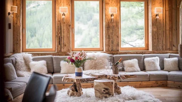 Une pièce chaleureuse avec une grande fenêtre à cadre en bois, un canapé agrémenté de coussins moelleux et une table basse en bois rustique.