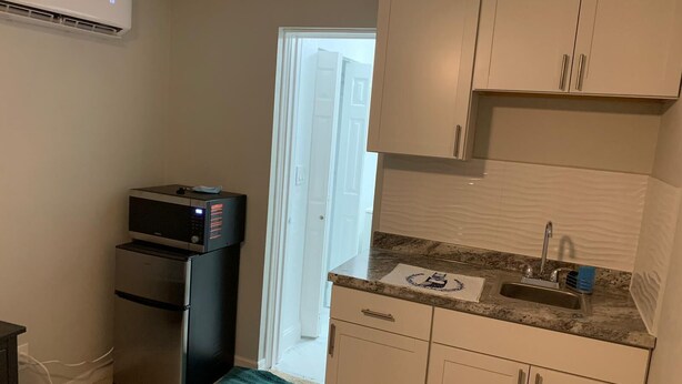 A compact kitchen with a refrigerator, microwave, sink, and cabinets.