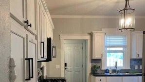 A kitchen with white cabinets, a black countertop, and a wooden floor.