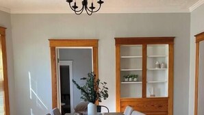 A dining area with a table, chairs, a chandelier, a potted plant, and a built-in shelving unit.
