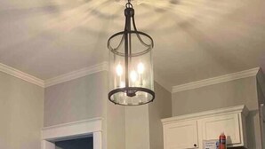 A kitchen with a stainless steel refrigerator, a trash can, and a ceiling light fixture.
