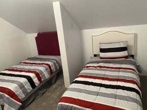 A bedroom with two single beds, each with striped bedding and a headboard.