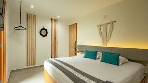 A bedroom with a large bed, wooden floor, a wooden door, a wall-mounted macrame, and a hanging black hanger. - Capital O Hotel Terraza 158 Mexico City (Mexico City)