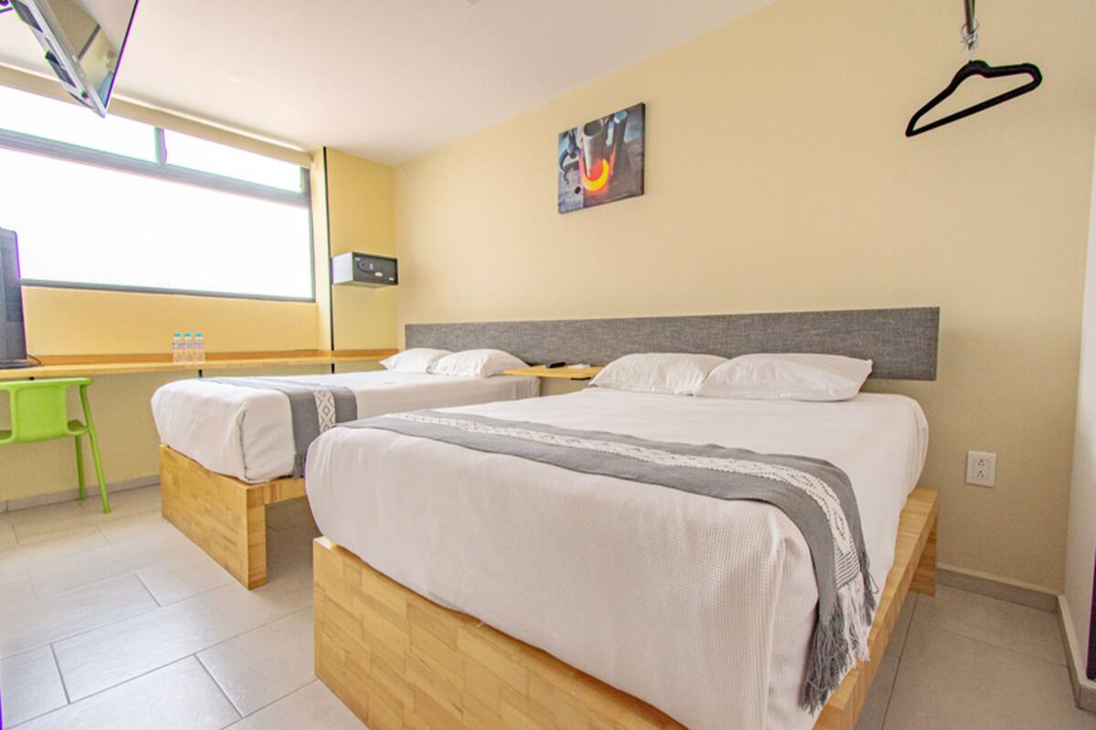 A hotel room with two beds, a desk, and a chair.