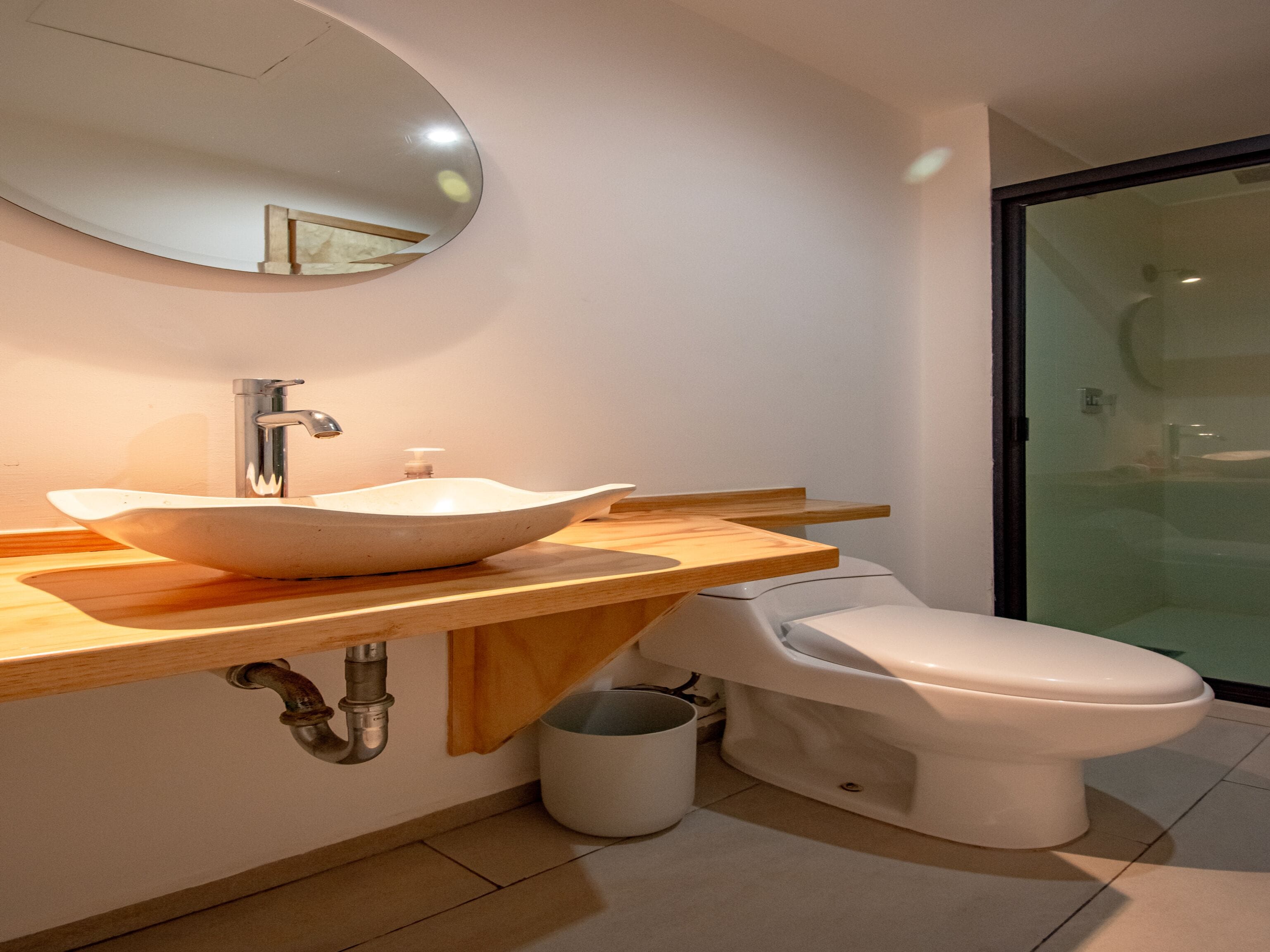 Een moderne badkamer met een wastafel, een ronde spiegel en een toilet.