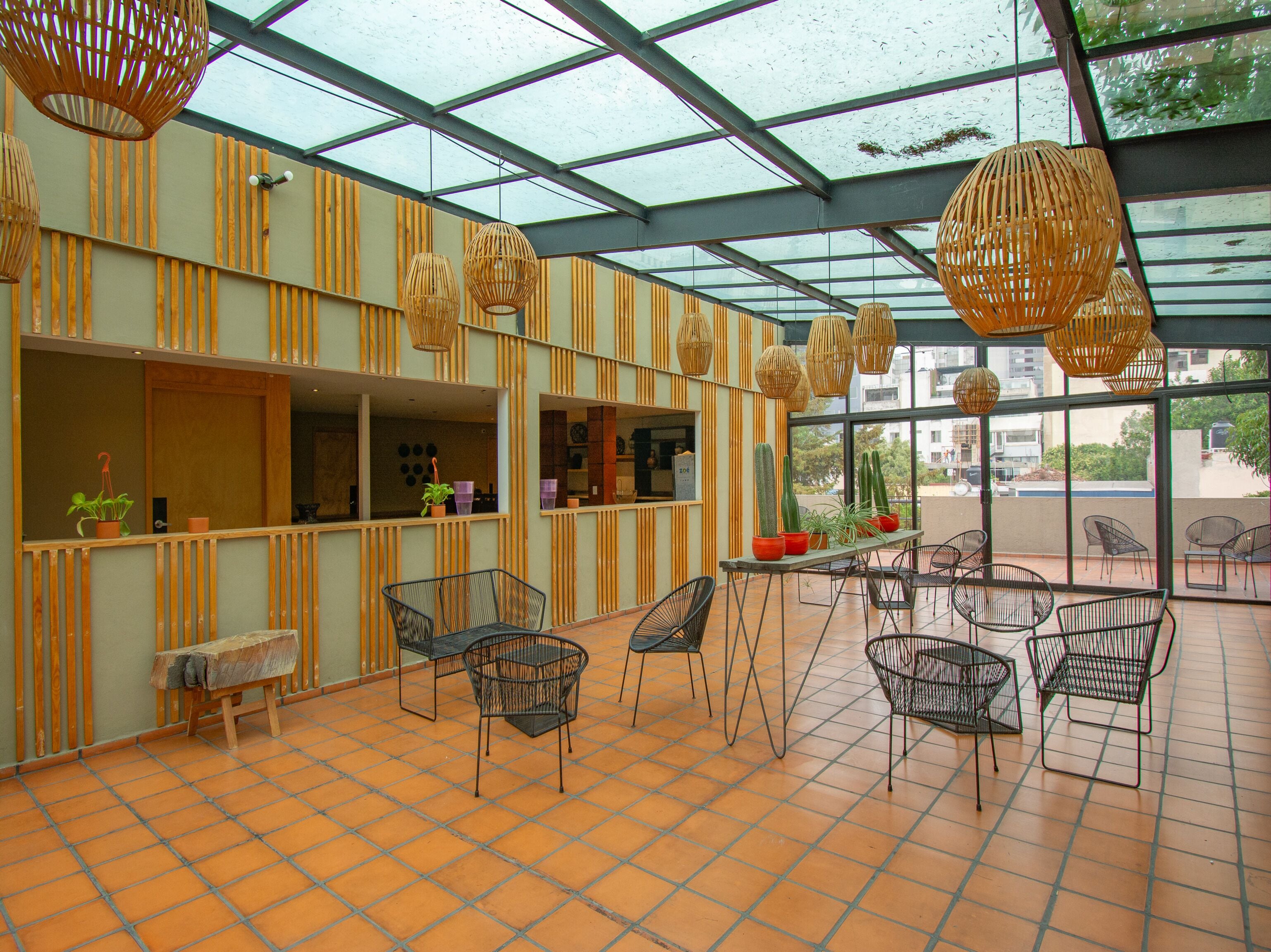 A restaurant with a glass ceiling, striped walls, and wicker hanging lights.
