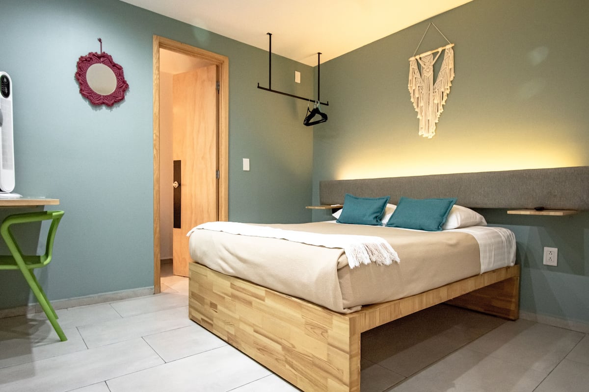 A bedroom with a wooden bed, a desk, and a chair.